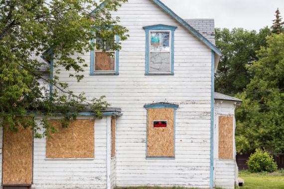 old-condemned-white-twostory-house-with-windows-boarded-up-picture-id505551799.jpg